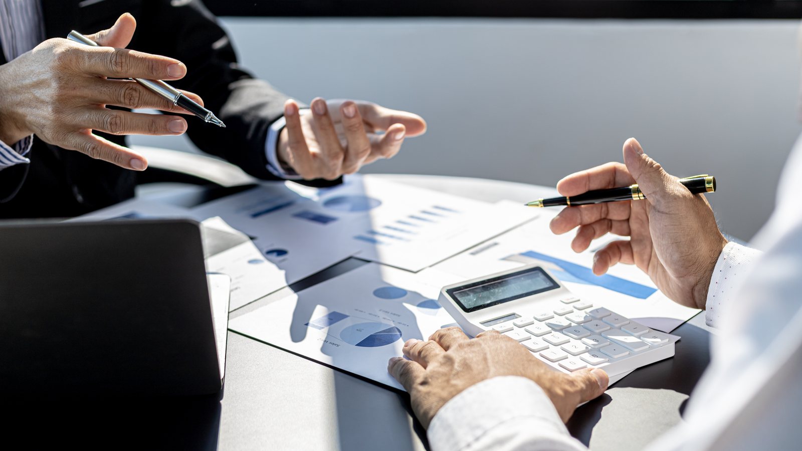 Due persone analizzano grafici di bilancio con calcolatrice e appunti