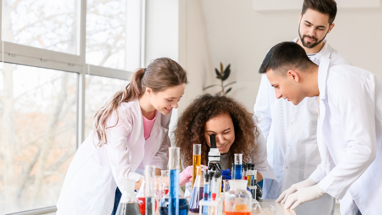 Studenti in camice al microscopio nel laboratorio di chimica