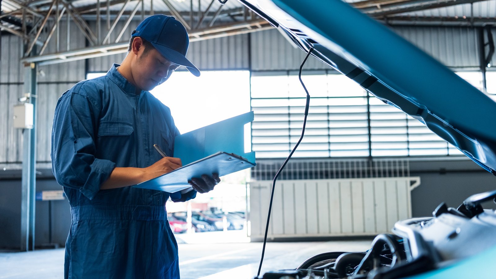 Tecnico in officina che compila una scheda di lavorazione davanti a un motore